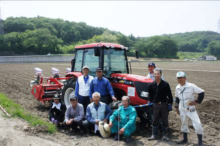 笑顔の七ヶ浜生産組合の皆さん。営農再開の日、支援したトラクターが「初稼働」した。